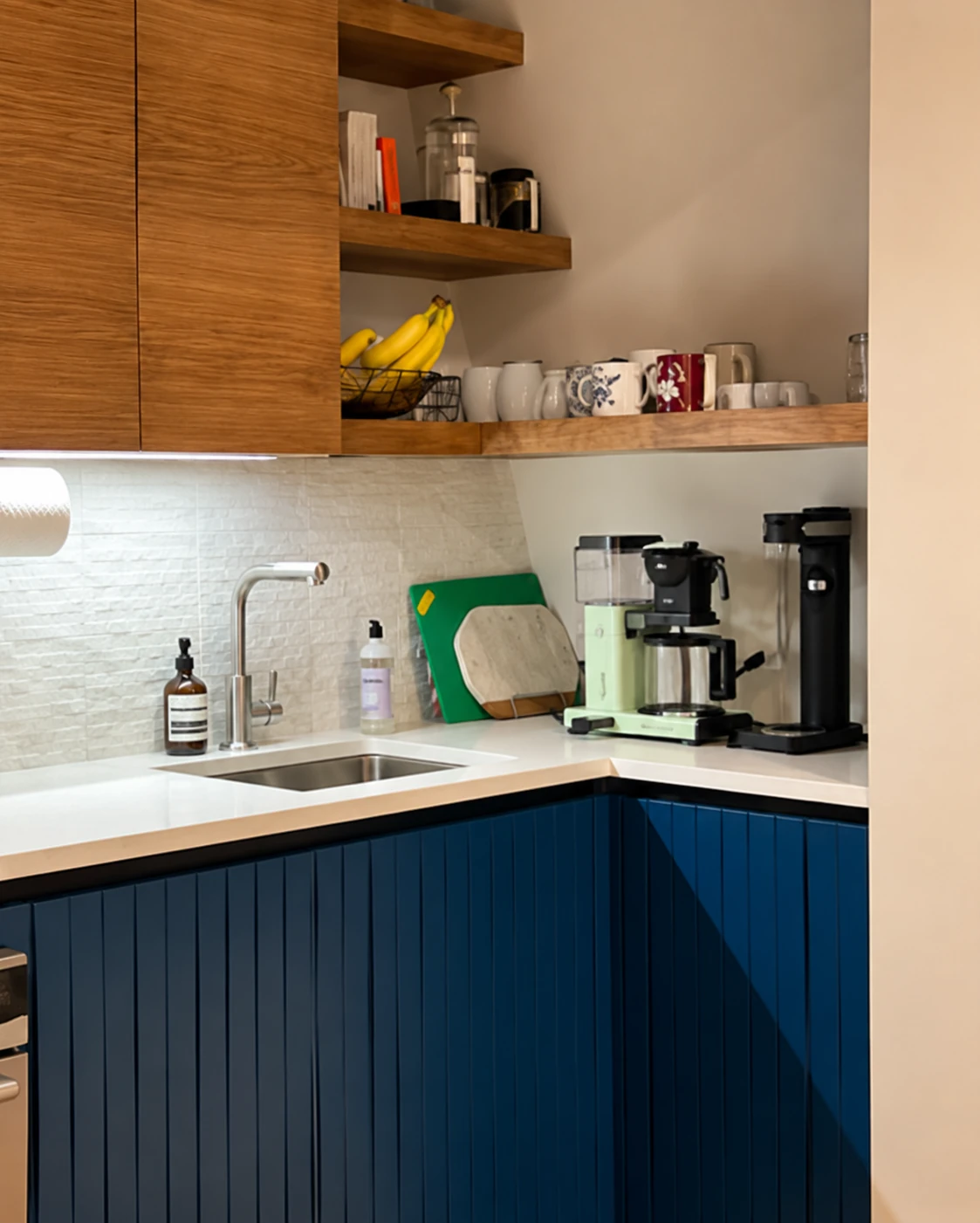Kitchen corner with blue lower cabinets, wood cupboards, and open shelving