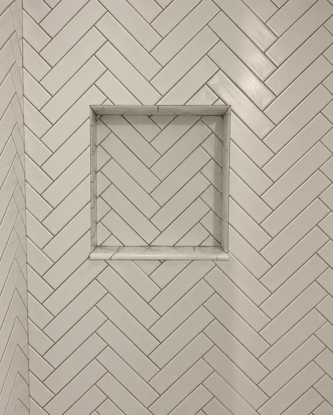 Herringbone shower wall tiles surrounding a recessed niche