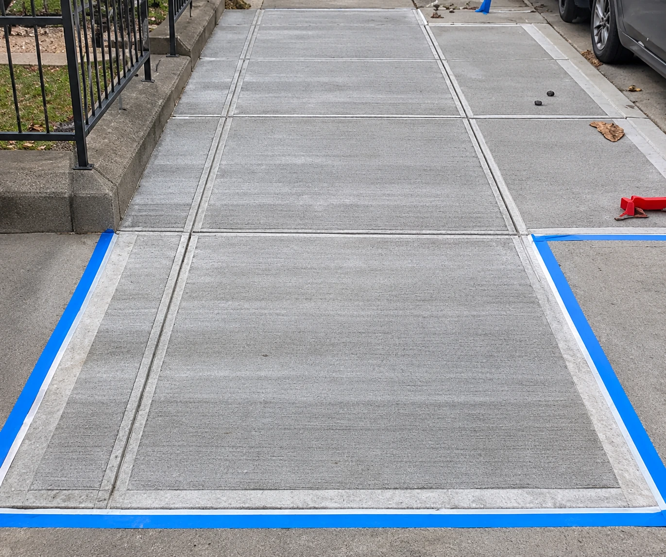 Concrete walkway with a textured surface, rectangular joints, and taped edges