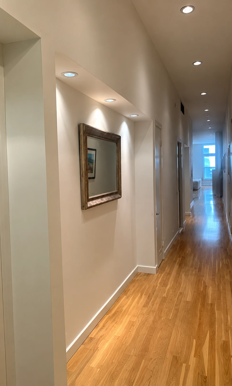 Long interior hallway with hardwood flooring and recessed ceiling lights