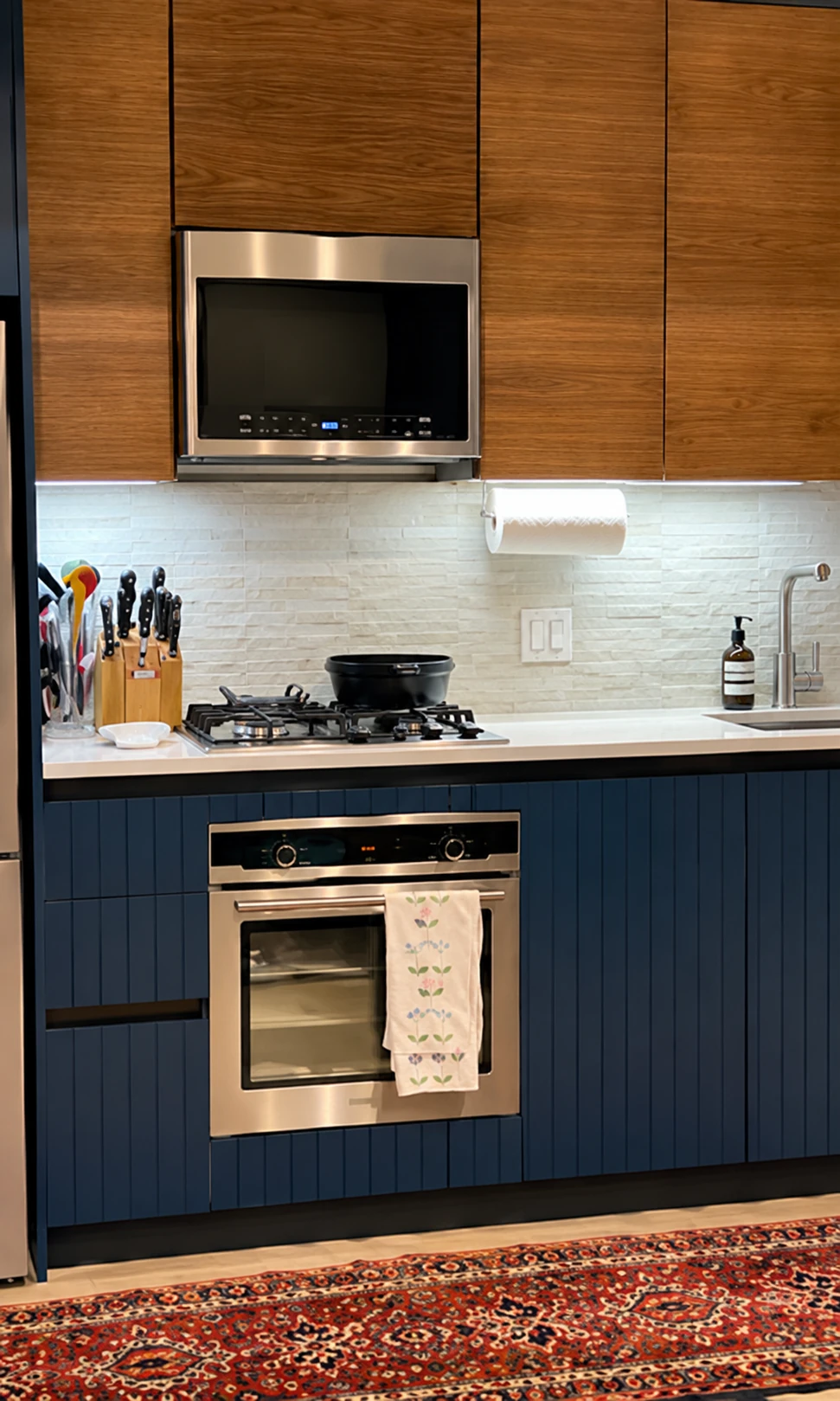 Kitchen with blue lower cabinets, wood upper cabinets, a built-in oven, and a microwave