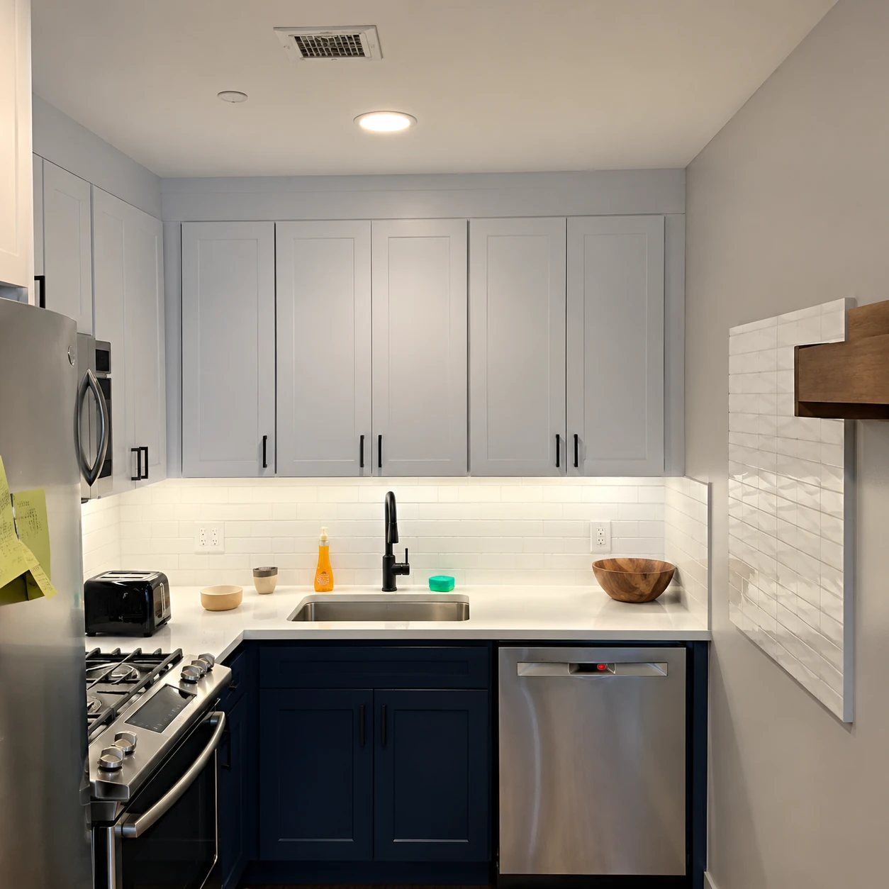 Compact kitchen with white upper cabinets and a stainless steel dishwasher