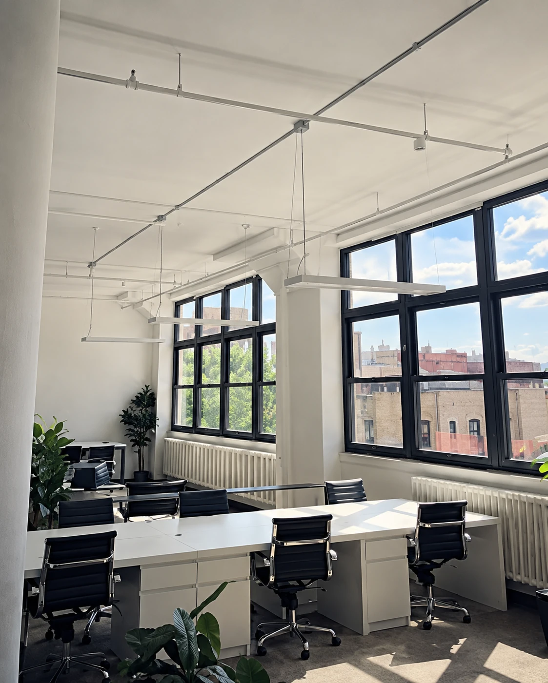 Bright office workspace with large windows and shared desks