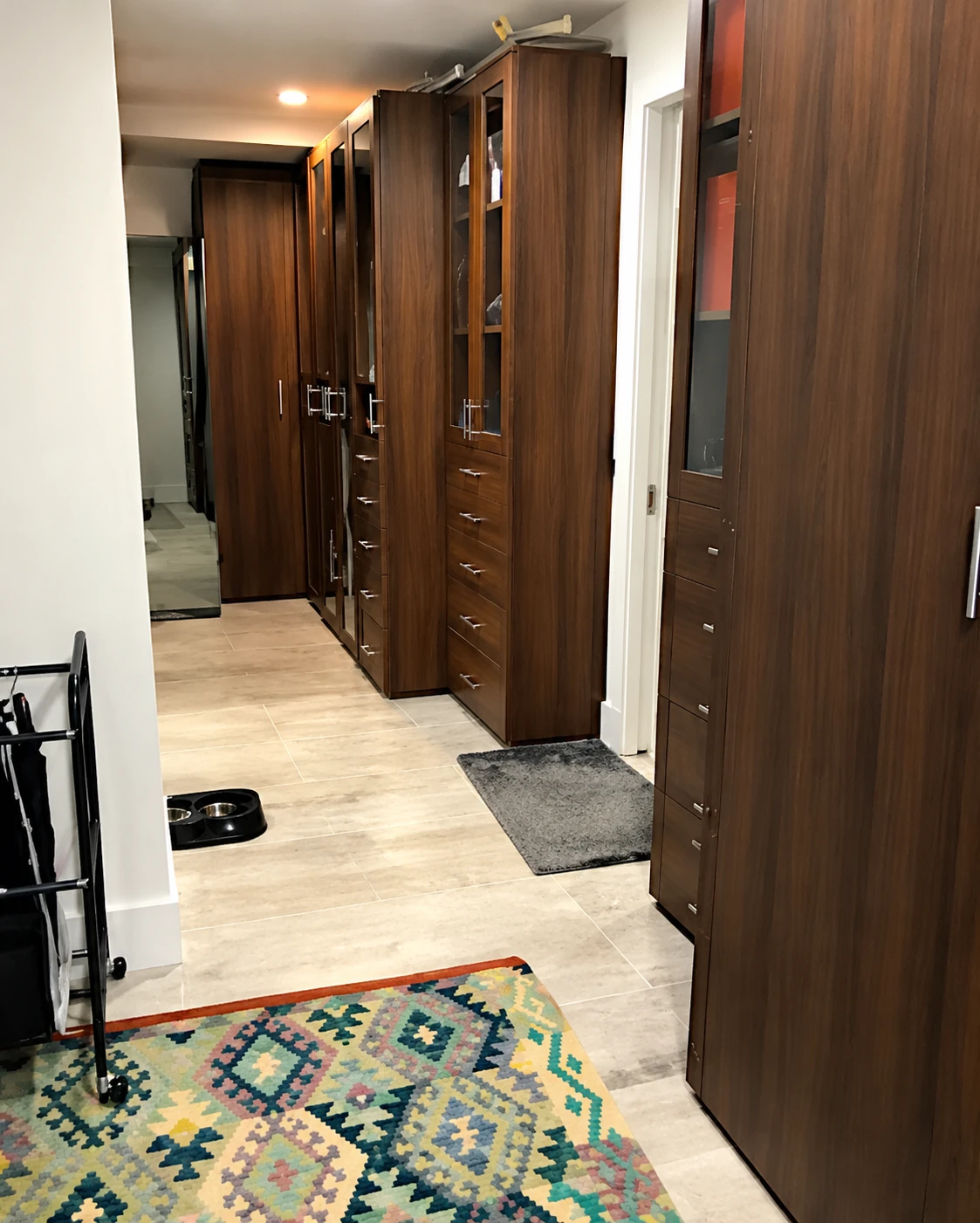Interior entry hall with dark wood doors, light floor tiles, and a patterned rug